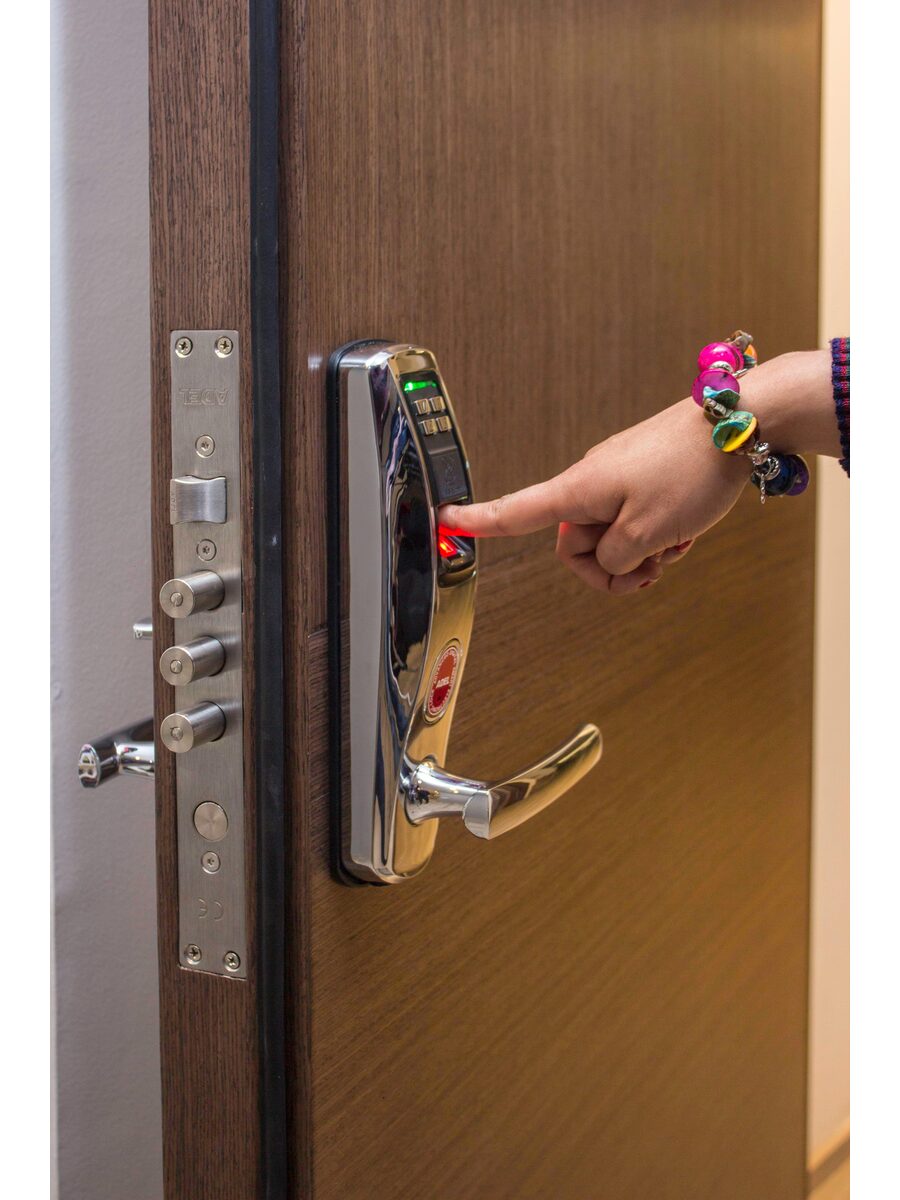 Hand pressing a smart door lock keypad — practical home security after leaving an abusive relationship